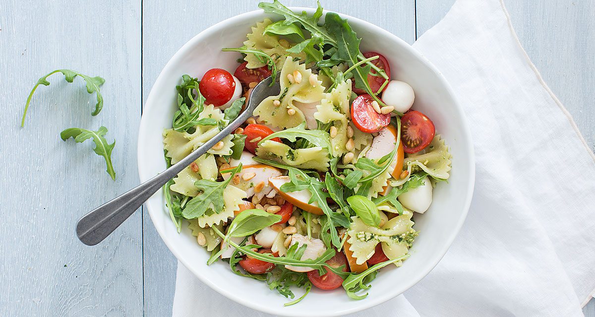 Diep bord gevuld met Pastasalade met pesto en kip