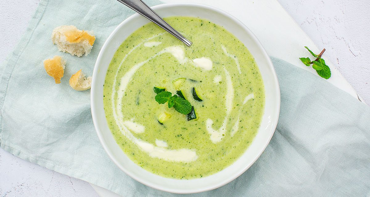 Kommetje courgettesoep met een vleugje room en muntblaadje