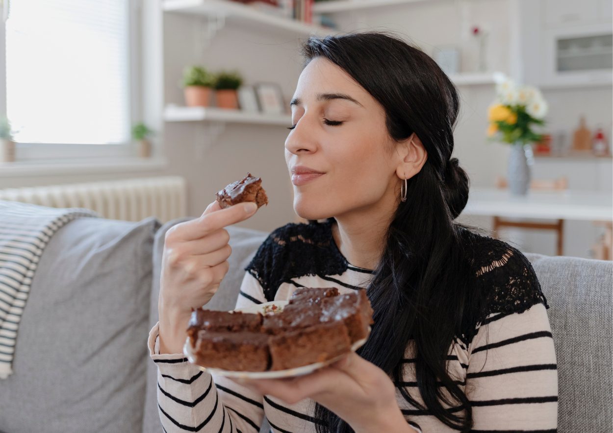 Vrouw geniet, met haar ogen dicht, van een heerlijke stuk coacoladetaart