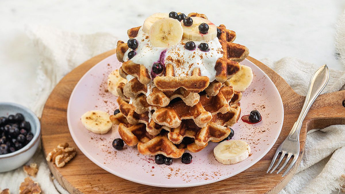 Bord met stapels wafels met topping van yoghurt en fruit