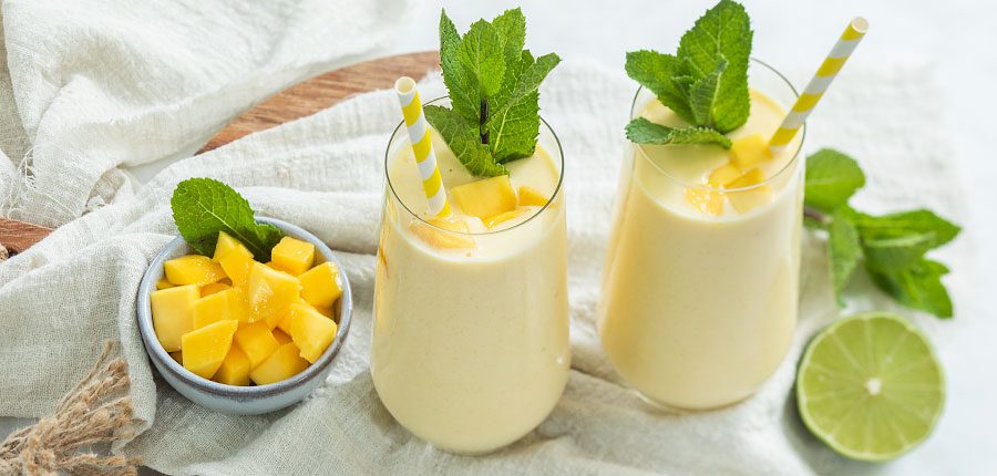 Glas gevuld met smoothie van mango en kokosyoghurt