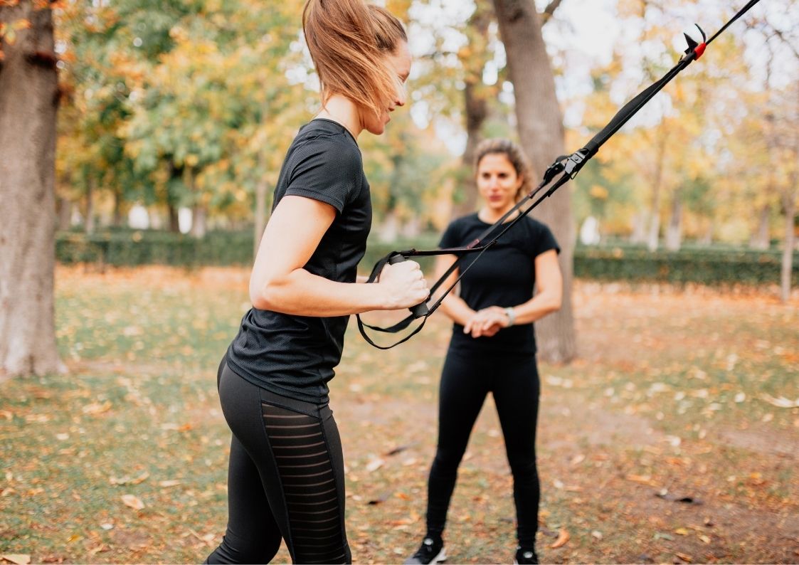 Vrouwelijke personal trainer traint vrouw buiten in het bos van Wageningen