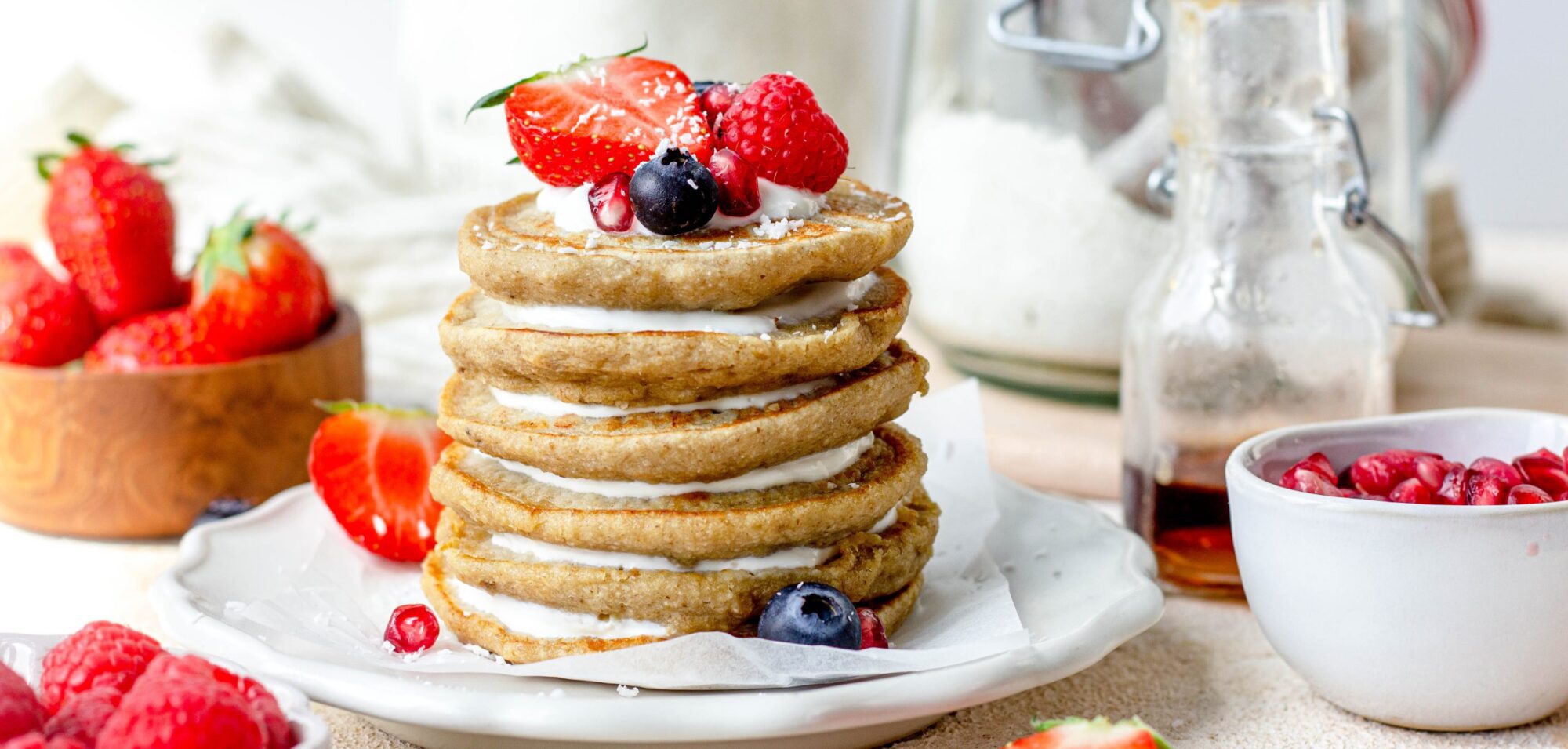 Bord met gestapelde pancakes met laagjes kwark en stukjes fruit als topping