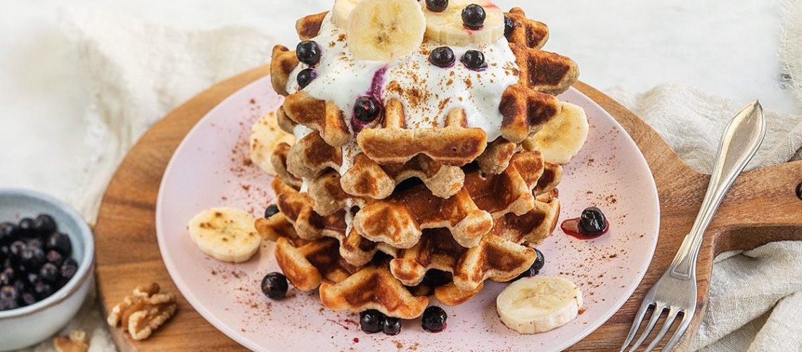 Bord met stapels wafels met topping van yoghurt en fruit