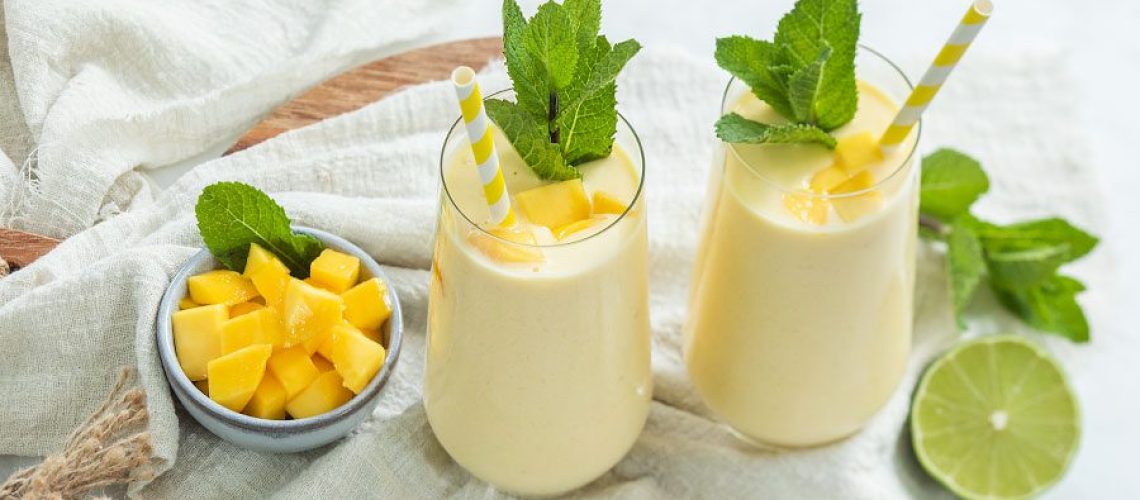 Glas gevuld met smoothie van mango en kokosyoghurt